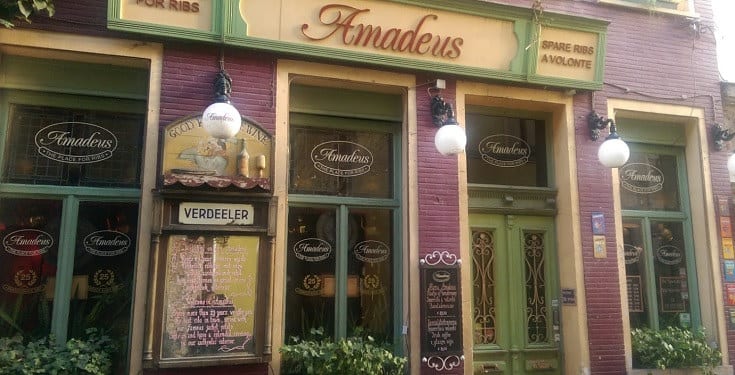 De bordeaux-groene gevel van Amadeus Gent 1 in het Patershol, met gouden Amadeus-belettering en ronde bollampen
