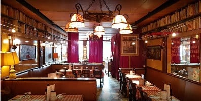 De zaal van Amadeus Brussel met glas-in-lood hanglampen, houten lambrisering en gedekte tafels