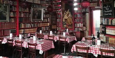 Boekenwanden tot aan het plafond boven de rood-wit geruite tafels van Amadeus Gent 1