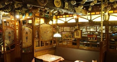 Art-nouveau houtwerk met glas-in-loodpanelen en koperen lampen in Amadeus Gent 1