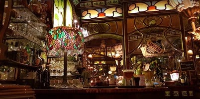 Een gekleurde glas-in-lood hanglamp boven de toog van Amadeus Gent 2