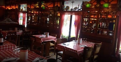 Het houten interieur van Amadeus Lozer met geruite gordijnen en rood-wit geruite tafels