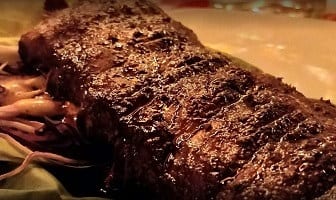 Close-up van een rek gegrilde ribbetjes bij Amadeus, met een donkere glanzende korst